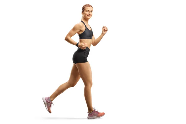 Spor kıyafetli fit bir kadın koşuyor ve kameraya bakıyor. — Stok fotoğraf