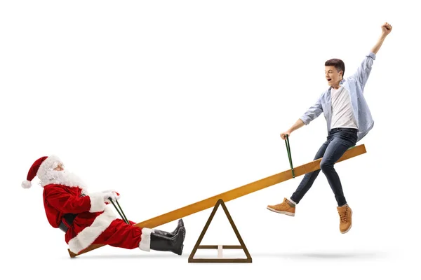 Jultomten och en lycklig manlig tonåring som leker på en gungbräda — Stockfoto