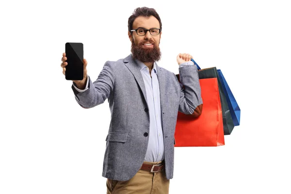 Skäggig man med shoppingväskor som visar en mobiltelefon — Stockfoto
