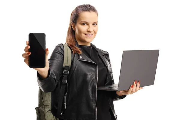 Mujer joven mostrando un teléfono móvil y sosteniendo un ordenador portátil — Foto de Stock