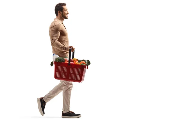 Fit man glimlachend en lopend met een mand met voedingsmiddelen — Stockfoto