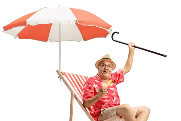 Turista masculino com um coquetel e uma bengala sentados em uma cadeira de praia — Fotografia de Stock