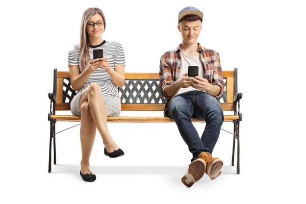 Jovem e uma adolescente sentada em um banco com telefones celulares — Fotografia de Stock