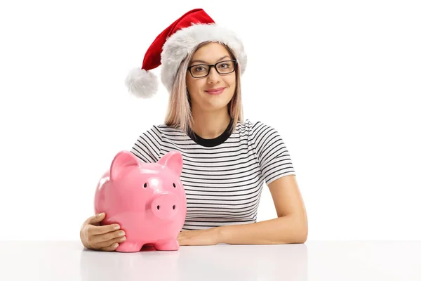 Woman wearing a Santa Claus hat sitting with a piggy bank and sm Stock Picture