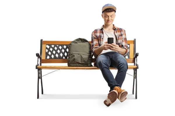 Adolescente masculino sentado em um banco e usando um telefone celular — Fotografia de Stock