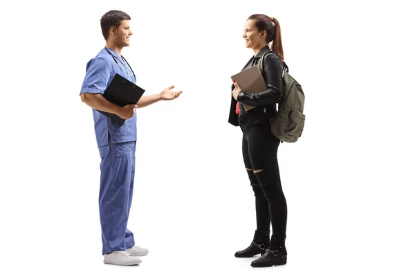 Male doctor in a blue uniform talking to a young female patient — Stock Photo, Image