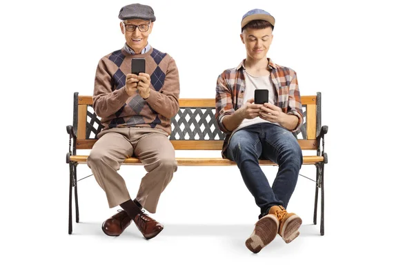 Пожилой человек и молодой парень, сидящий на скамейке и пользующийся мобильным телефоном — стоковое фото