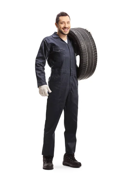 汽车修理工拿着车胎对着摄像机笑 — 图库照片