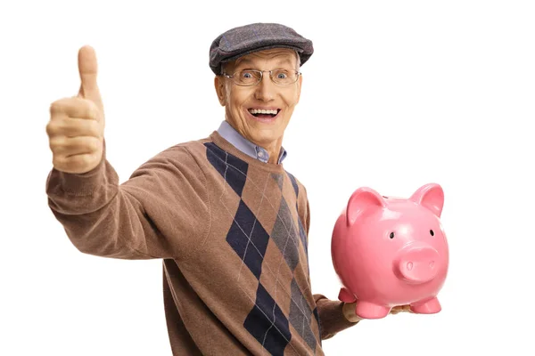 Šťastný starší muž drží prasátko banky a ukazující palec nahoru — Stock fotografie