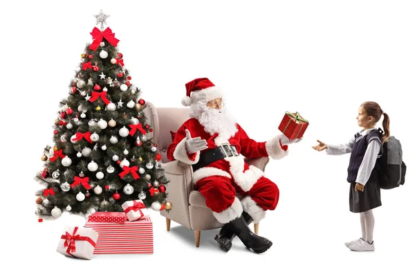 Santa Claus with a Christmas tree giving a present to a schoolgi — Stock Photo, Image