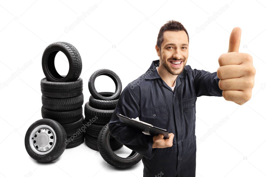 Mechanic with tires holding a clipboard and showing thumbs up