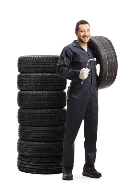 Auto mechanic holding a tire and a lug wrench — Stock Photo, Image