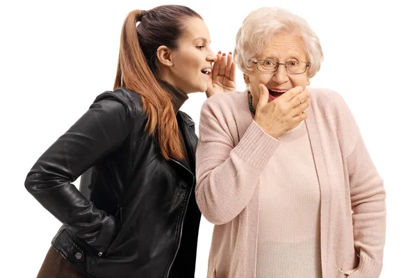 Молодая женщина шепчет удивленной пожилой женщине — стоковое фото