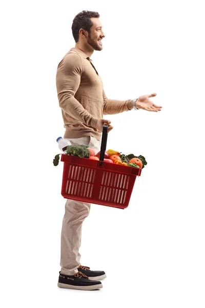 Man holding a shopping basket and gesturing with hand — Stock Photo, Image