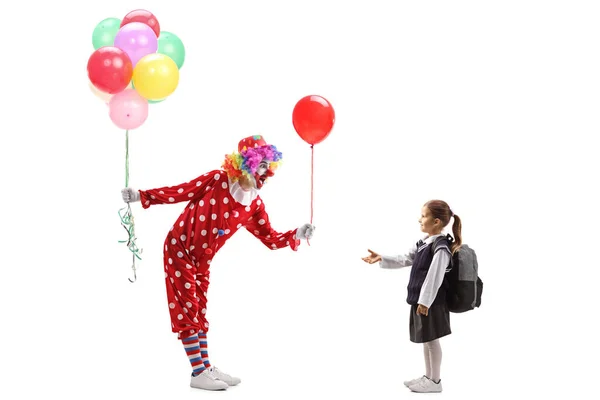 Clown håller i ett gäng ballonger och ger en till en liten sch — Stockfoto
