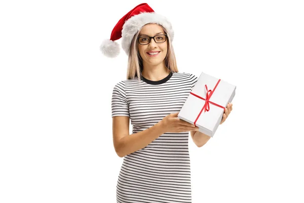 Lächelnde junge Frau mit Weihnachtsmütze, die ein Geschenk in der Hand hält und posiert — Stockfoto