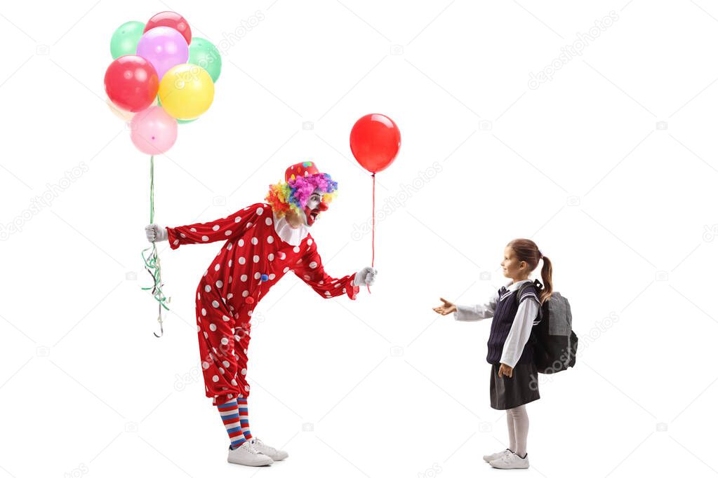 Clown holding a bunch of balloons and giving one to a little sch