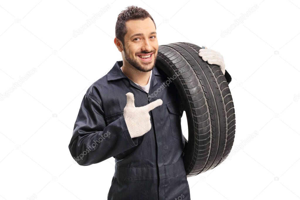 Car mechanic carrying a tire and pointing