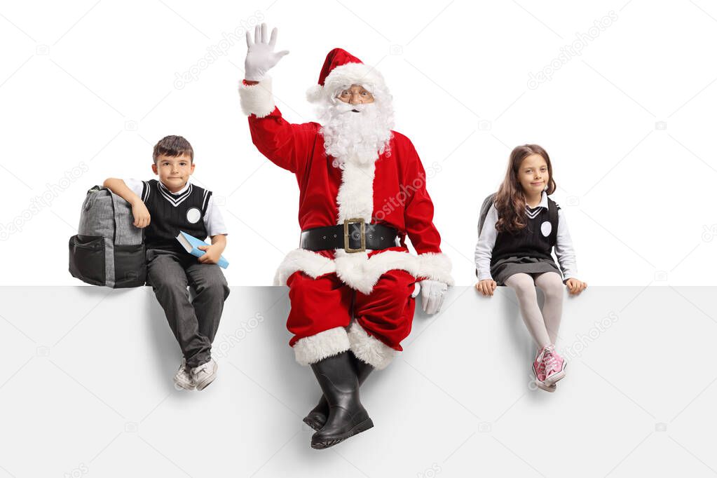 Santa Claus waving and sitting on a panel with schoolchildren