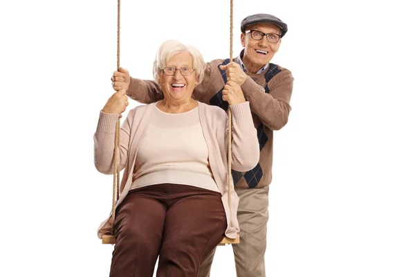 Elderly man pushing an elderly woman on a swing — Stock Photo, Image