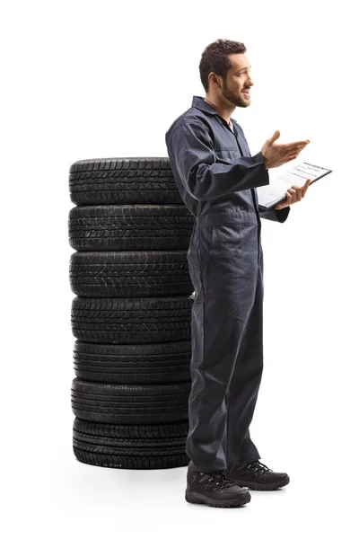 Mecânico de carro com uma pilha de pneus gesticulando com a mão — Fotografia de Stock