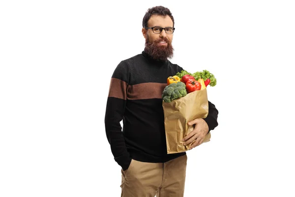 Бородатий чоловік позує з паперовим мішком, повним фруктів і овочів — стокове фото