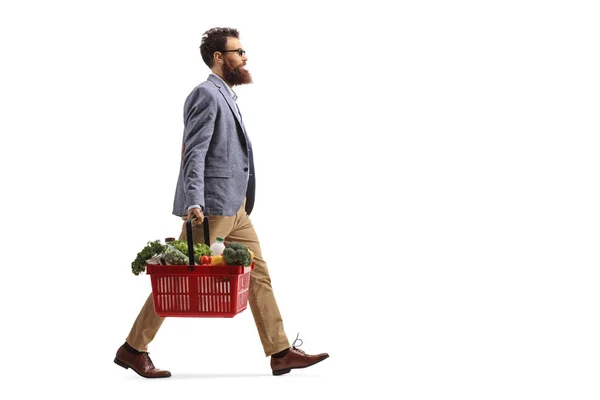 Uomo barbuto che cammina e trasporta un cesto della spesa con cibo — Foto Stock