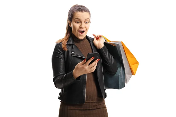 Surprise jeune femme avec des sacs à provisions en regardant son mobile p — Photo