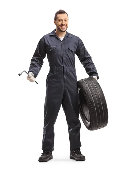 Auto mechanic holding a wrench and a tire — Stockfoto