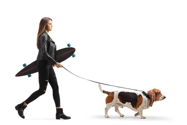 Young female holding a longboard and walking a basset hound dog — Stock Photo, Image