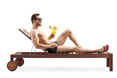 Yakışıklı genç adam güneşleniyor ve kokteyl içiyor.