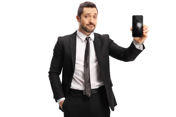 Грустный молодой человек в костюме показывает сломанный экран на мобильном телефоне — стоковое фото