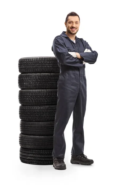 Carro mecânico posando com uma pilha de pneus — Fotografia de Stock