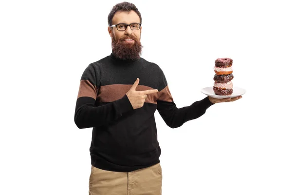 Бородатий чоловік тримає тарілку пончиків і вказує — стокове фото