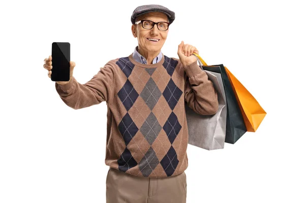 Starszy pan pokazuje telefon komórkowy i trzyma zakupy ba — Zdjęcie stockowe
