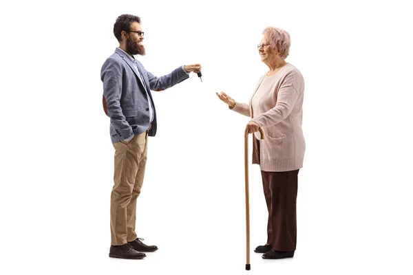 Bearded man giving car keys to an elderly woman with a walking c — Stock Photo, Image