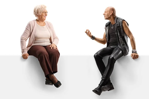 Punker praat met een oudere vrouw terwijl ze op een leeg paneel zit — Stockfoto