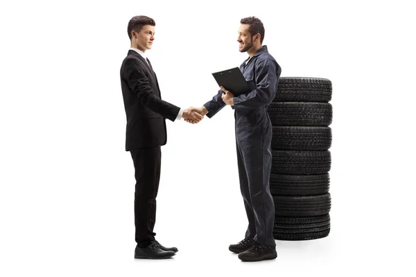 Automechaniker beim Händeschütteln mit einem jungen Mann im Anzug — Stockfoto