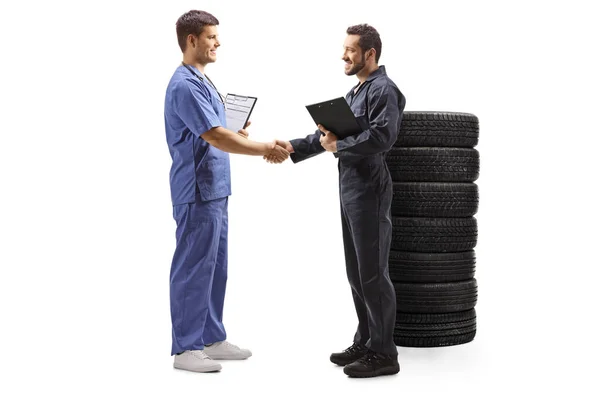 Otomobil tamircisi mavi üniformalı bir erkek doktorla el sıkışıyor. — Stok fotoğraf