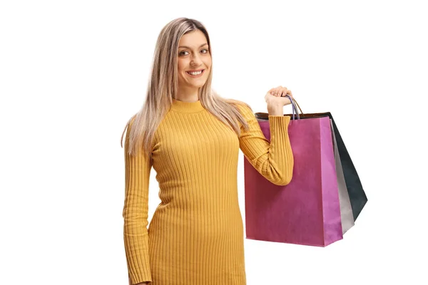 Joven mujer rubia sonriendo y sosteniendo bolsas de compras — Foto de Stock