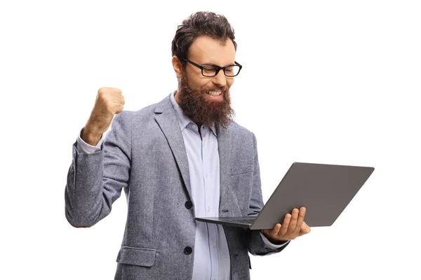 Barbudo hombre con un gesto de éxito y mirando a una compu portátil —  Fotos de Stock