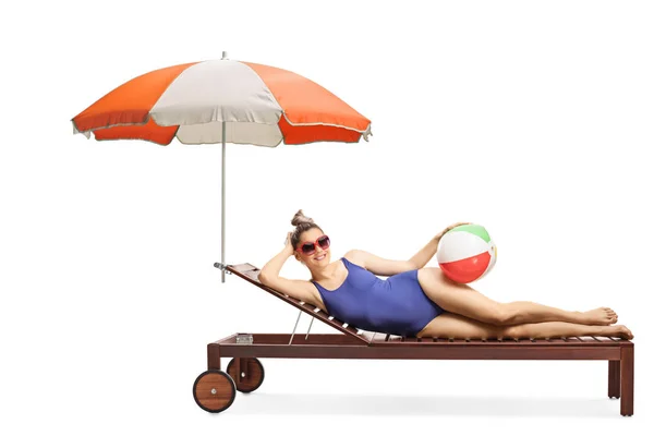 Kvinna med solglasögon och baddräkt liggande på en solsäng under — Stockfoto