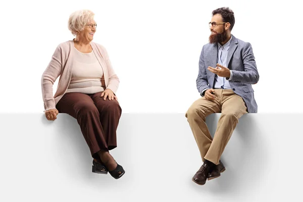 Senior woman and a bearded man sitting on a panel and talking — Stock Photo, Image