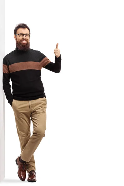 Bearded man in a turtleneck sweater leaning on a wall and showin — Stock Photo, Image