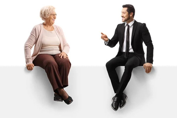 Бизнесмен разговаривает со старшей леди и сидит на панели — стоковое фото