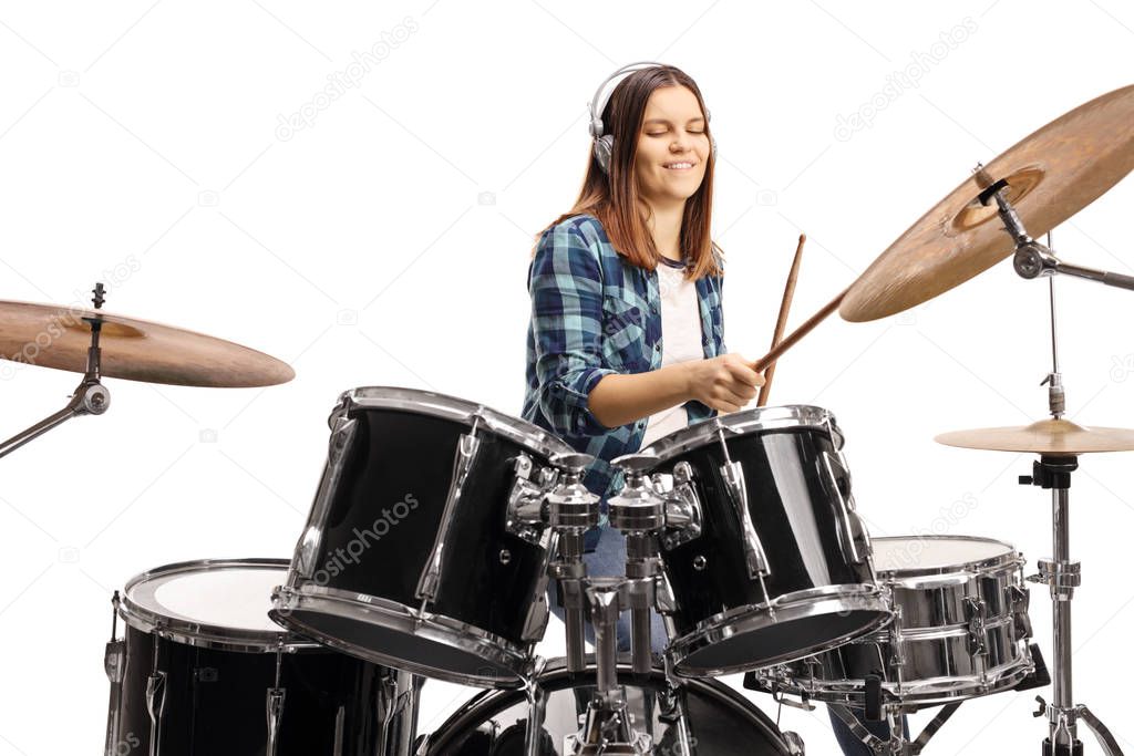 Female teenager with headphones playing drums