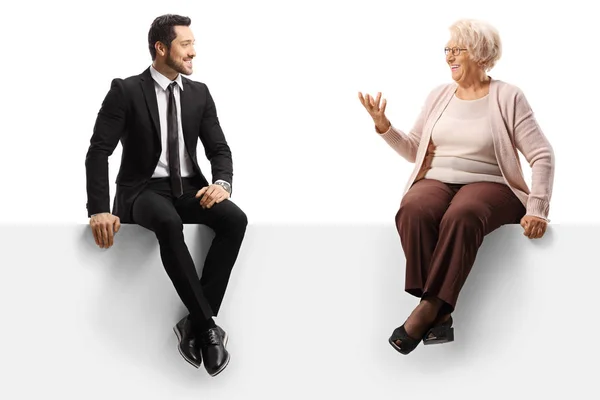 Empresário e uma mulher idosa sentados em um painel e conversando — Fotografia de Stock