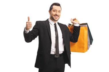 Takım elbiseli ve kravatlı yakışıklı bir adam alışveriş çantaları taşıyor ve gösteriş yapıyor.