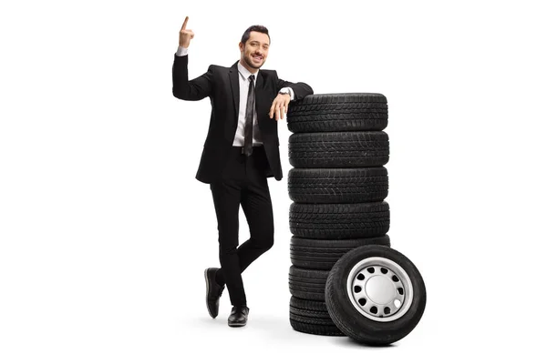 Young businessman pointing above and leaning on a pile of car ti — Stock Photo, Image