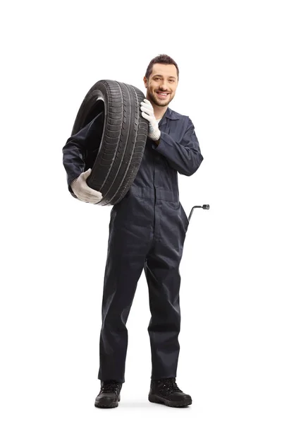 Mécanicien automobile portant un pneu et souriant à la caméra — Photo
